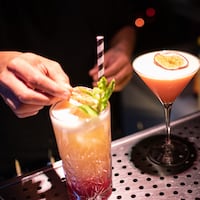 A bartender garnishes a cocktail.