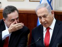 Israeli Prime Minister Benjamin Netanyahu listens to Foreign Minister Israel Katz who has his hand over his mouth.