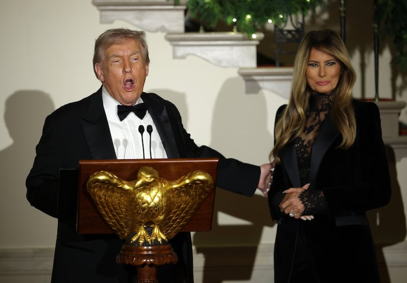 U.S. President Donald Trump delivers remarks as first lady Melania Trump looks during the Congressional Ball at the Grand Foyer of the White House on December 11, 2025 in Washington, DC.