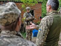 Three Ukrainian soldiers talk outside in Zolochiv