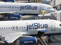 Two JetBlue planes parked at an airport.