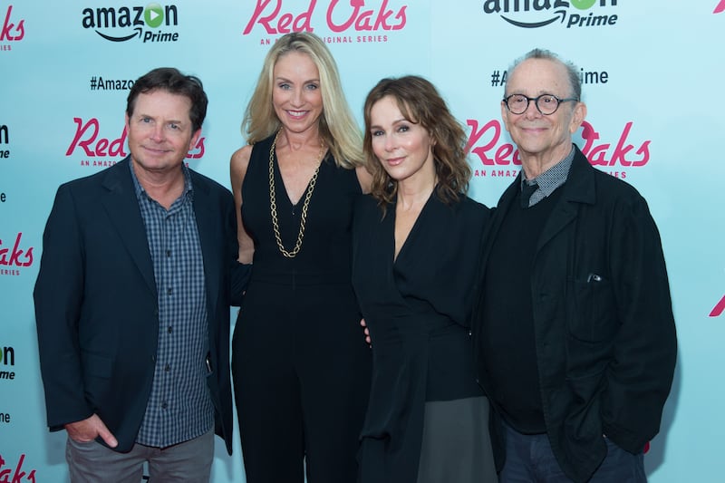 Michael J. Fox, Tracy Pollan, Jennifer Grey, and her father, Joel Grey, pose on the red carpet as they attend the “Red Oaks” series premiere in 2015.