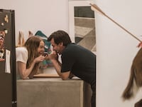 Emma Stone and Nathan Fielder hold hands and laugh over a counter in a still from 'The Curse'