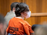 Ethan Crumbley, wearing a mask and an orange prison jumpsuit, stares forward in court.