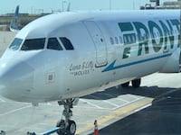 A photo of a Frontier Airlines plane parked at the gate.
