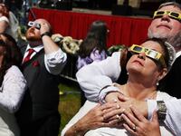 Two brides and grooms look up at the solar eclipse from an Arkansas field.