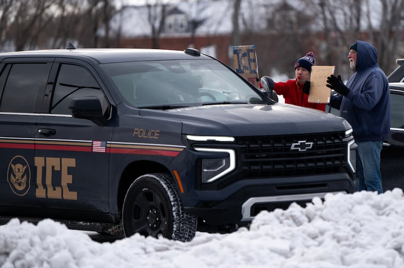 People confront an agent in an ICE vehicle near the regional ICE headquarters