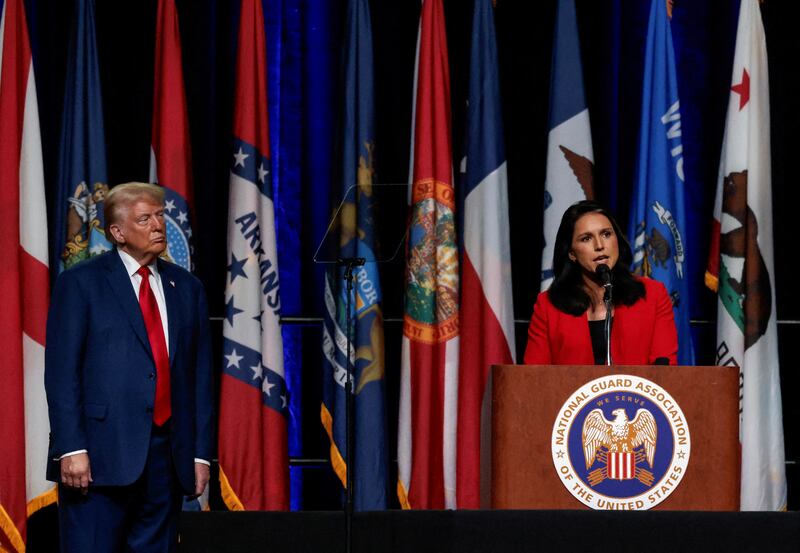 Donald Trump stands on stage while Tulsi Gabbard speaks into a microphone.