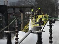 Two firefighters in a crane spray foam on a fire at an electrical substation at London Heathrow Airport.