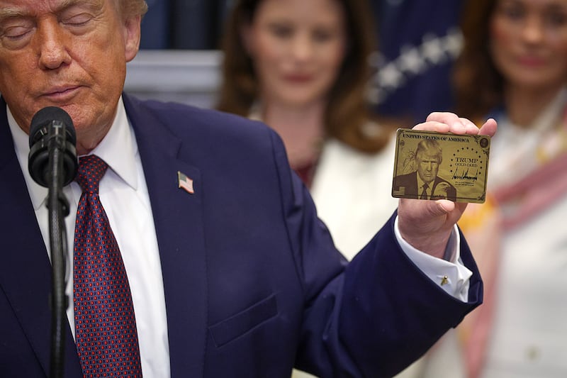 President Donald Trump holds a "Trump Gold Card" during an event in the White House on December 19, 2025 in Washington, D.C.