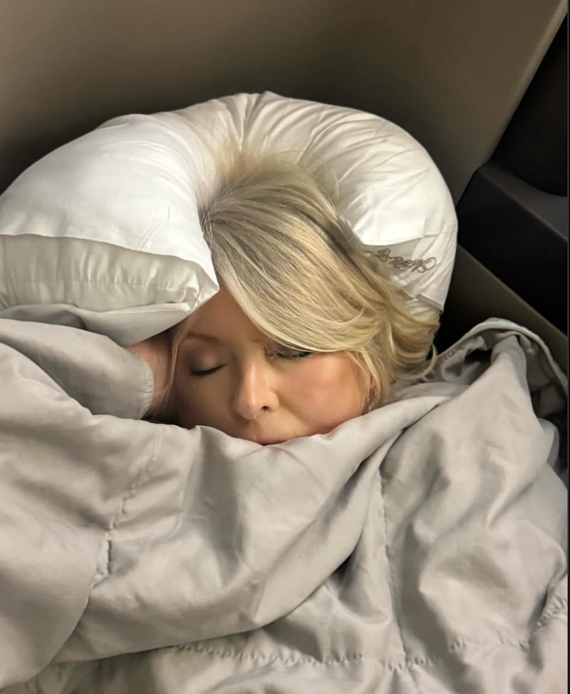 Martha Stewart’s Instagram post shows her sleeping on a flight with a pillow and blanket.