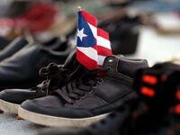 shoes holding puerto rico flag death toll maria katrina counting death statistic demography george washington harvard university climate change global warming
