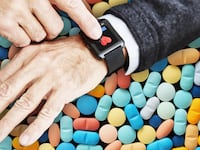 photo of hand with fitbit fit bit showing heart over tablets and pills john hancock insurance company west virginia life health fitness tracker