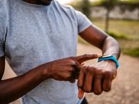 Athlete check fitness tracker on smartwatch or playing his music playlist after training in nature.