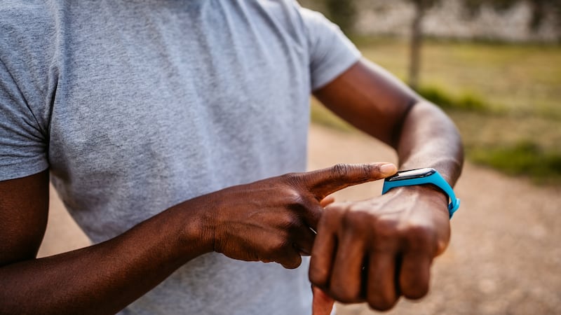 Athlete check fitness tracker on smartwatch or playing his music playlist after training in nature.