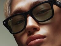 A person with blonde hair wearing a pair of Ray-Ban Meta Wayfarer smart glasses.