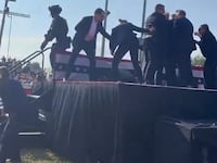 Behind-stage view of Secret Service agents shielding Donald Trump.