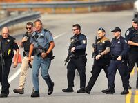 Heavily armed police walk near near the boat launch in the Androscoggin River on Rt 196 where suspect Robert Card abandoned his car.