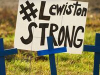 A memorial of blue crosses and a poster reading “Lewiston Strong.”