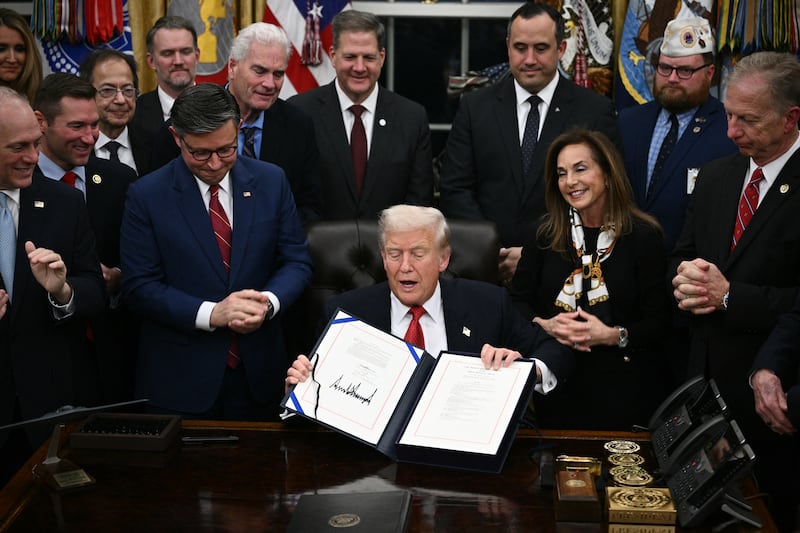 US President Donald Trump shows the signed bill package to re-open the federal government in the Oval Office of the White House in Washington, DC, on November 12, 2025.