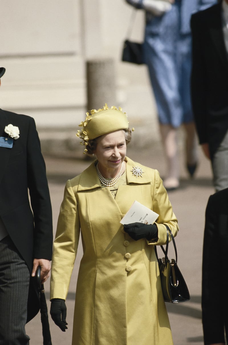 Queen Elizabeth II pictured wearing a yellow ensemble by British designer Ian Thomas at a Royal Ascot race meeting in Berkshire, England, in June 1985.