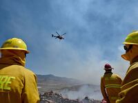 Banning, CA - June 30: Firefighters stand along Highway 243, also known as the Esperanza Firefighters Memorial Highway, as a helicopter flies in to make a water drop near Banning during the Wolf Fire on Monday, June 30, 2025. As of 2 p.m. the fire had burned 1,400 acres and was 30 percent contained following a heavy aerial attack. (Photo by Will Lester/Inland Valley Daily Bulletin via Getty Images)