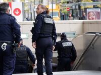 French police officers stand at the entrance of a metro station after a woman making threats on an RER train was shot and wounded by police, in Paris on October 31, 2023.