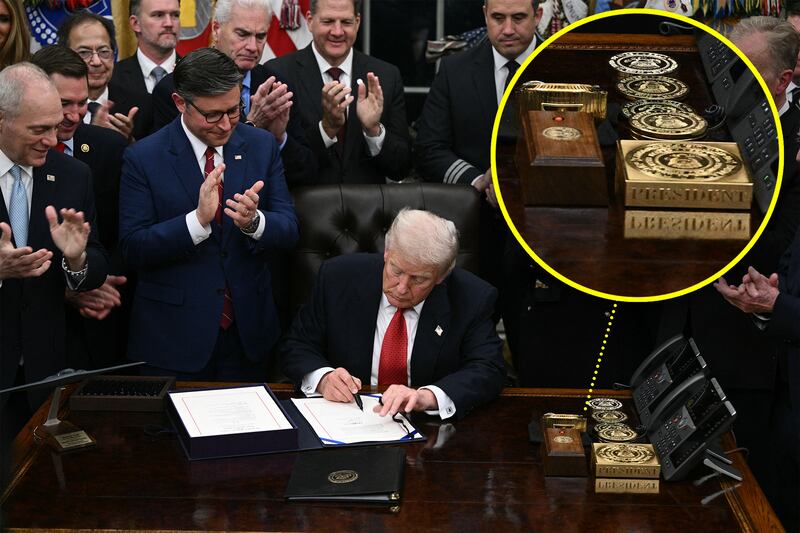 Donald Trump signs the bill package to re-open the federal government in the Oval Office of the White House in Washington, DC, on November 12, 2025, with a circle highlighting an enlarged part of the image showing a gold bar and Rolex clock on Trump's desk