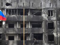A Russian national flag flies by destroyed buildings in Mariupol on April 12, 2022.