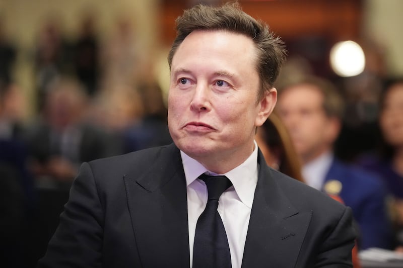 Elon Musk listens as Donald Trump addresses a House Republicans Conference meeting at the Hyatt Regency on Capitol Hill on November 13, 2024