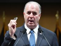 Dan Kildee holds up a shard of glass while speaking.
