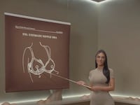 Kim Kardashian uses a pointer to direct attention to a diagram of her shapewear line's new Ultimate Nipple Bra.