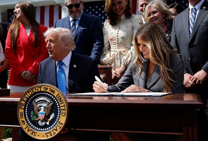 Melania Trump signs the TAKE IT DOWN Act alongside U.S. President Donald Trump, lawmakers and victims of AI deepfakes and revenge porn, during a signing ceremony in the Rose Garden of the White House on May 19, 2025 in Washington, DC. The first lady made the Tools to Address Known Exploitation by Immobilizing Technological Deepfakes on Websites and Networks (TAKE IT DOWN) Act a priority, traveling to Capitol Hill to lobby lawmakers and show her support for the legislation, which addresses non-consensual intimate imagery, or "revenge porn," and artificial intelligence deepfakes posted online and to social media. (Photo by Chip Somodevilla/Getty Images)