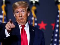 Donald Trump makes a face and points while on stage at a campaign event.