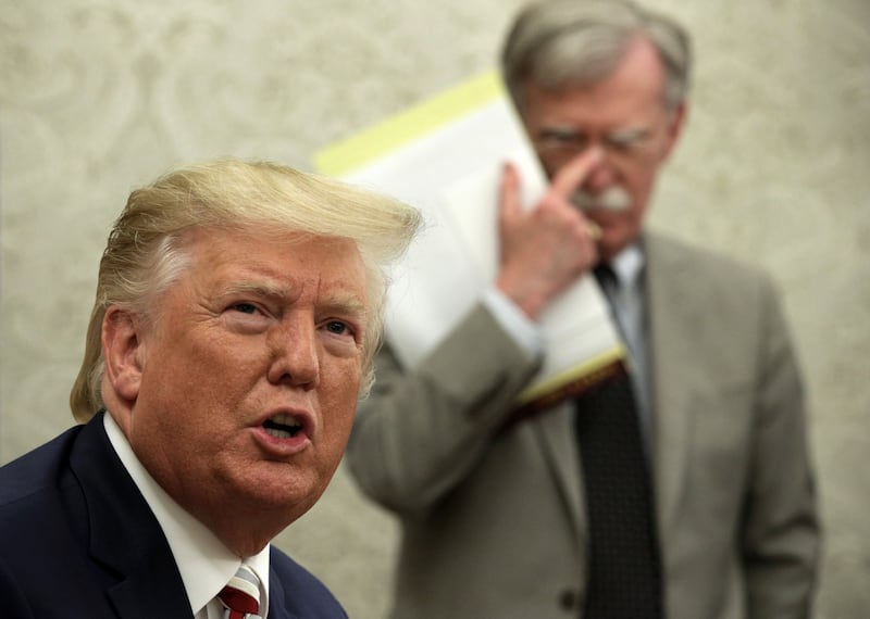 President Donald Trump speaks to members of the media as National Security Adviser John Bolton listens during a meeting with President of Romania Klaus Iohannis in the Oval Office of the White House August 20, 2019 in Washington, DC.
