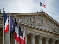 French flags are seen by a side of the facade of the National Assembly