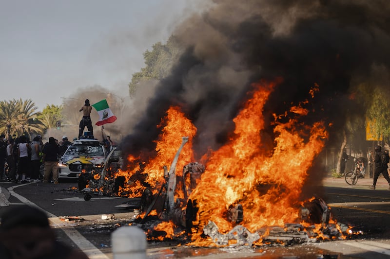 Several cars burn on North Los Angeles street during clashes between protesters and police on June 8, 2025 in Downtown Los Angeles, California. The clashes come after ICE raids swept throughout the city over the weekend.