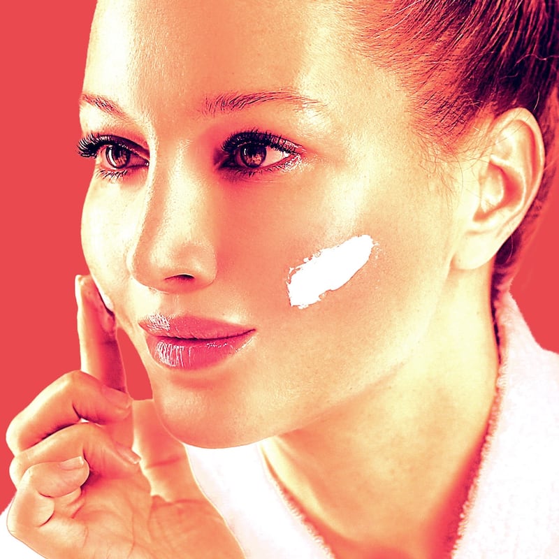 A woman applies a cleaning balm on her cheeks.
