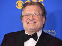 Drew Carey stands against a blue background