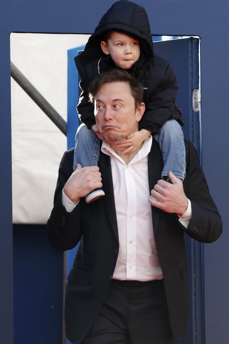 Elon Musk holds one of his children on his shoulders as he arrives to attend a 2023 meeting organized by the Italian far right Fratelli d'Italia governate party in Rome.