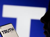 The Truth social network logo displayed behind a woman holding a smartphone.
