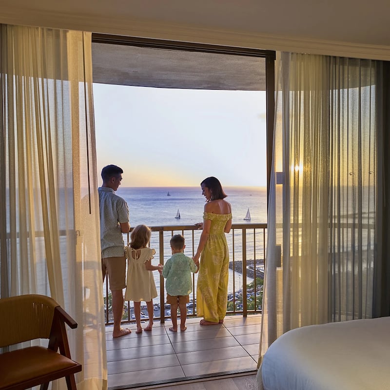 Family standing on a balcony at a Hilton residence overlooking a body of water