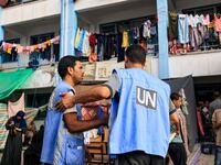 Workers of the UNRWA) agency talk together in the playground of an UNRWA-run school that has been converted into a shelter for displaced Palestinians in Khan Yunis in the southern Gaza Strip on October 25, 2023.