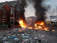 Riot police hold back protesters near a burning police vehicle after disorder broke out on July 30, 2024 in Southport, England.