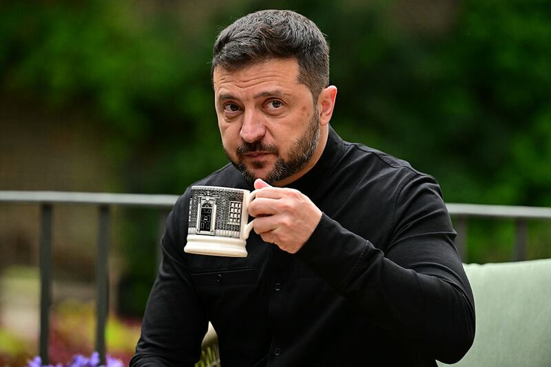 LONDON, ENGLAND - AUGUST 14: Ukraine's President Volodymyr Zelensky drinks from a Downing Street -themed mug as he sits with Britain's Prime Minister Keir Starmer (unseen) in the garden of 10 Downing Street on August 14, 2025 in London, United Kingdom. Zelenskyy's UK visit comes following his trip to Berlin to attend virtual meetings with European leaders and US President Trump to discuss the strategy for talks taking place between Trump and Russian President Vladimir Putin on Friday in Alaska, where they will discuss ending the war in Ukraine. (Photo by Ben Stansall - WPA Pool/Getty Images)