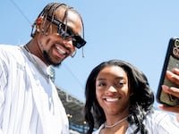 Jonathan Owens smiles alongside Simone Biles on the field at a baseball game.