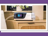 The ResMed AirSense 11 CPAP Machine on a nightstand in a lit bedroom.