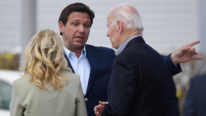 Florida Governor Ron DeSantis (C), US President Joe Biden (R) and First Lady Jill Biden (L) chat during a visit.