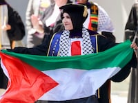 Graduate Malak Afaneh waves a Palestinian flag as she crosses the stage to receive her degree during the UC Berkeley Law School commencement at the Greek Theater in Berkeley Friday, May 10, 2024.