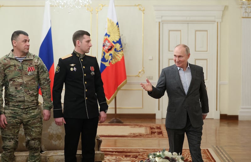 A photo including Russia's President Vladimir Putin with service members
